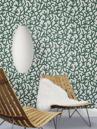 Green abstract print wallpaper with wooden lazy chairs and low hanging white lantern