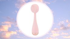 pale pink PMD Clean facial cleansing brush on a pastel pink and blue cloud background