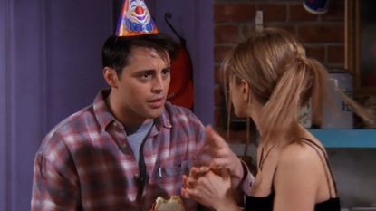 Joey from Friends talks to Rachel with a clown party hat on his head