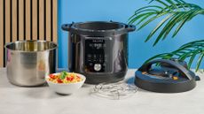 a black instant pot with a dial and touchpad is photographed against a blue background