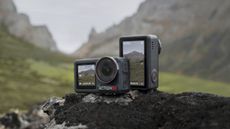 Two DJI Osmo Action 5 Pro cameras on a rock, front and back, with mountain backdrop