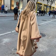 Eliza Huber wearing a tan, fur-trim, cape-style coat by By Malene Birger on the street in New York.