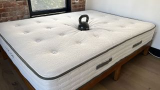 The Avocado Green mattress on a bed with a weight on it