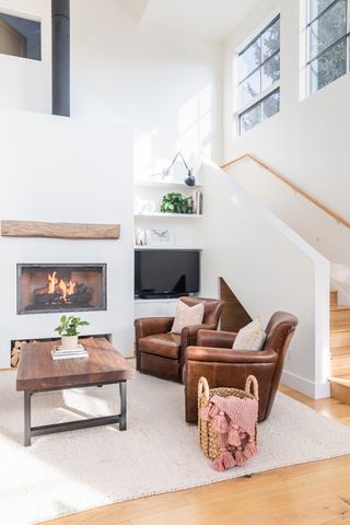 S modern living room idea with cassette fireplace, wooden coffee table, brown leather armchairs and TV