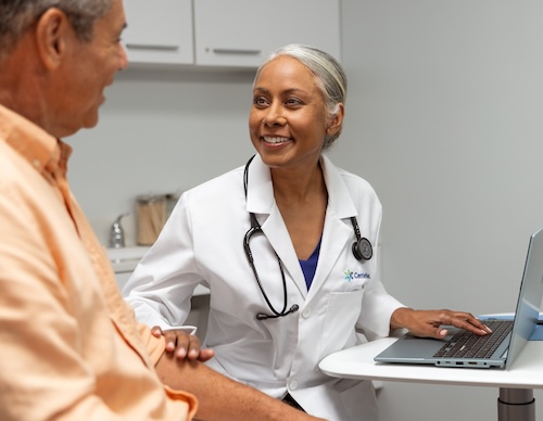 An attentive physician speaking with a male patient seated in a chair during a visit.