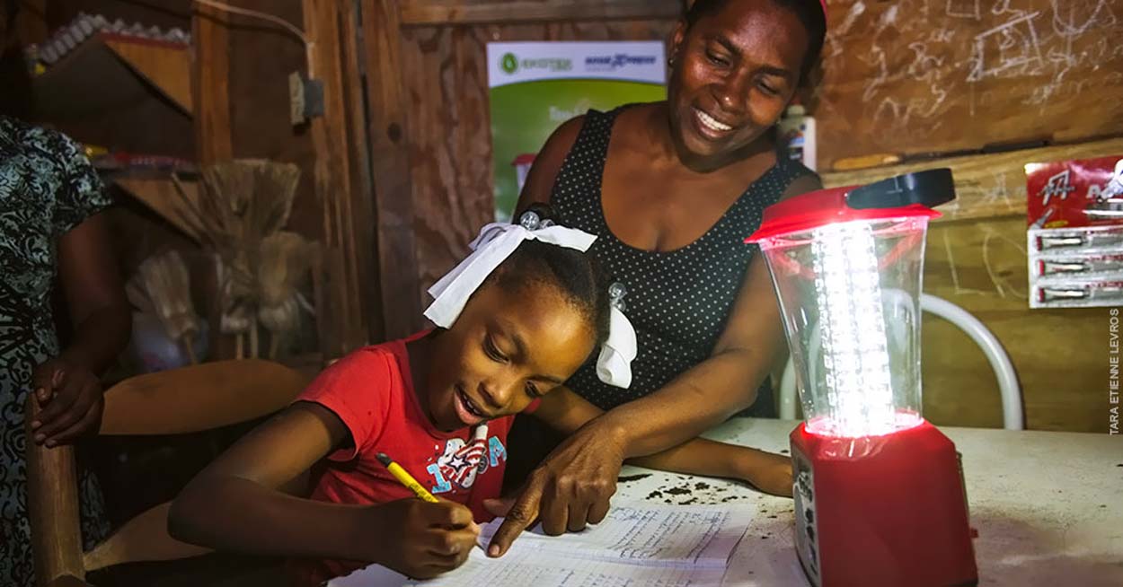 A mother and daughter use a lantern while working on homework