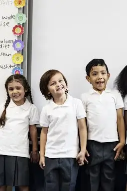 three children in white polos smiling