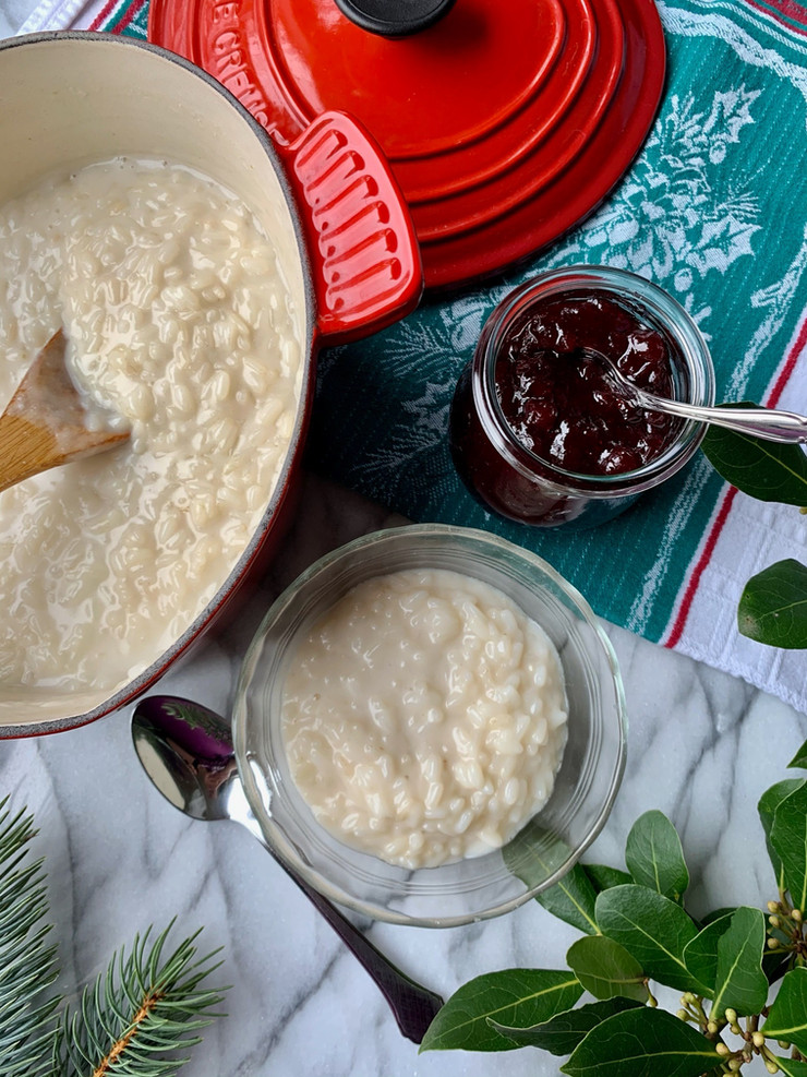 Rice pudding served in a glass dish next to a jar of red lingonberries