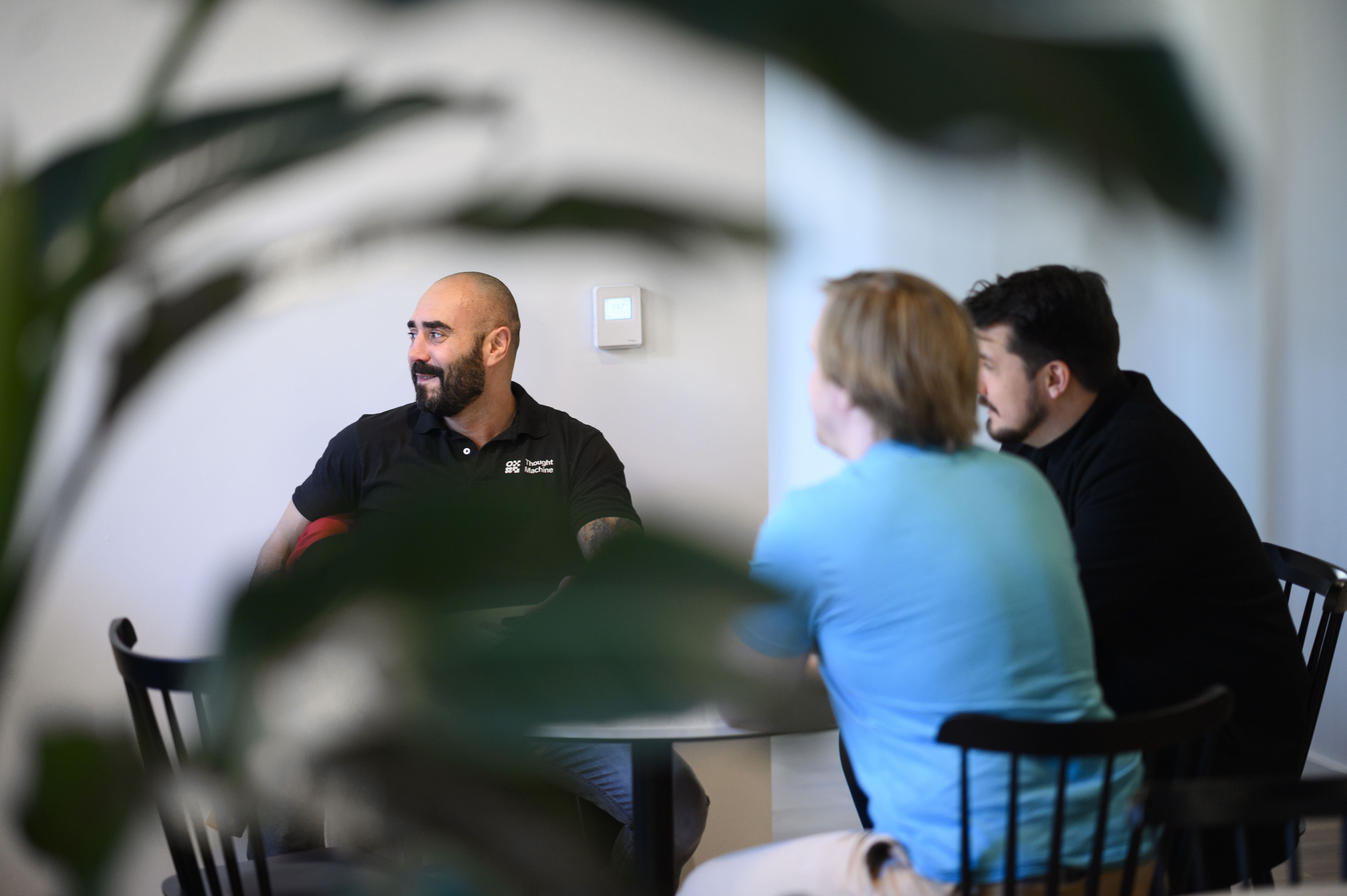 Thought Machine employees gathered around a table discussing a topic