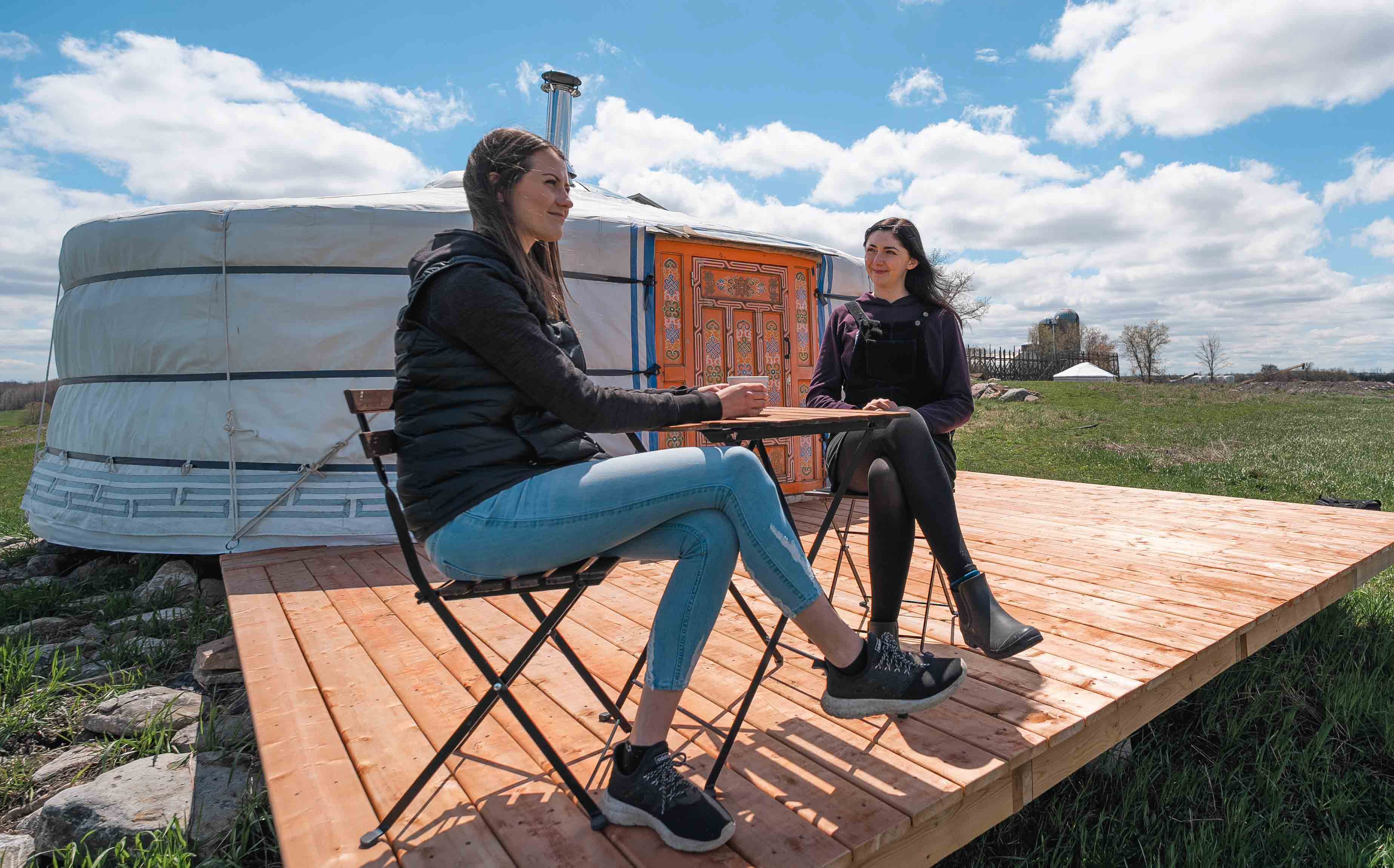 Two persons sitting at a table outside of fully insulated yurt.