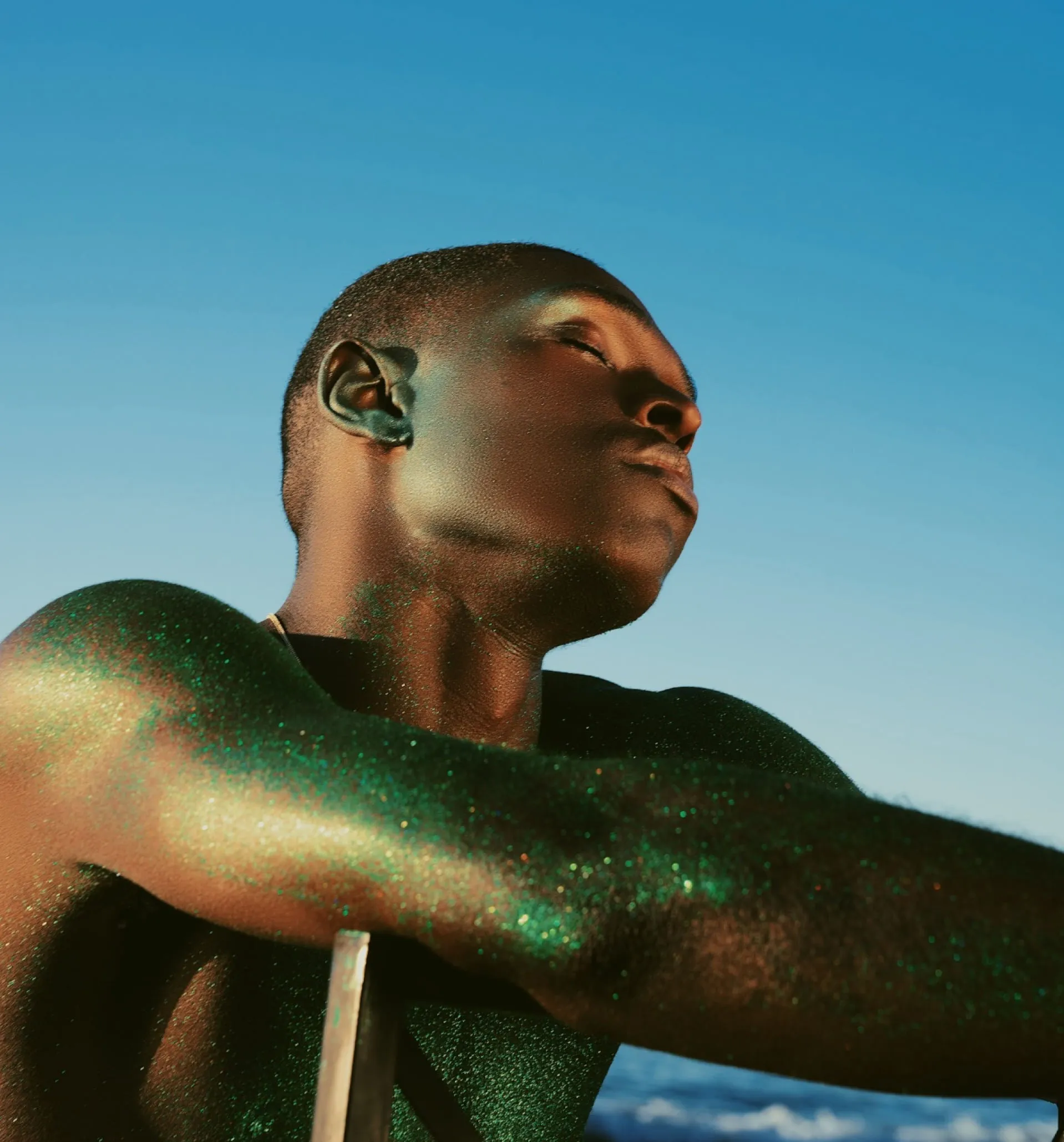 Portrait of a man with eyes closed covered in glitter against blue sky original photo before VSCO edits