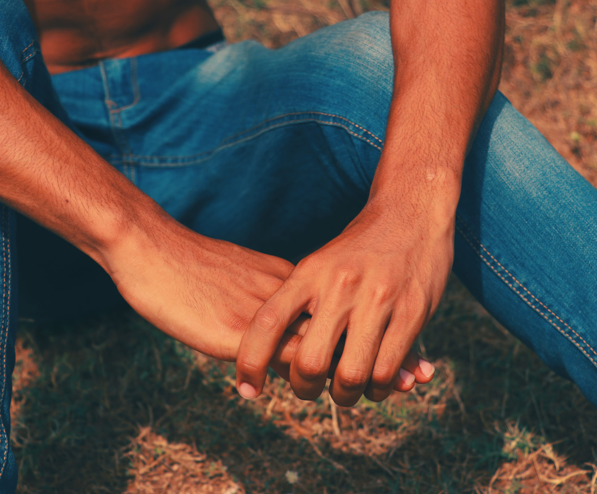 Person sitting with arms on knees wearing blue jeans before being edited with VSCO photo filters