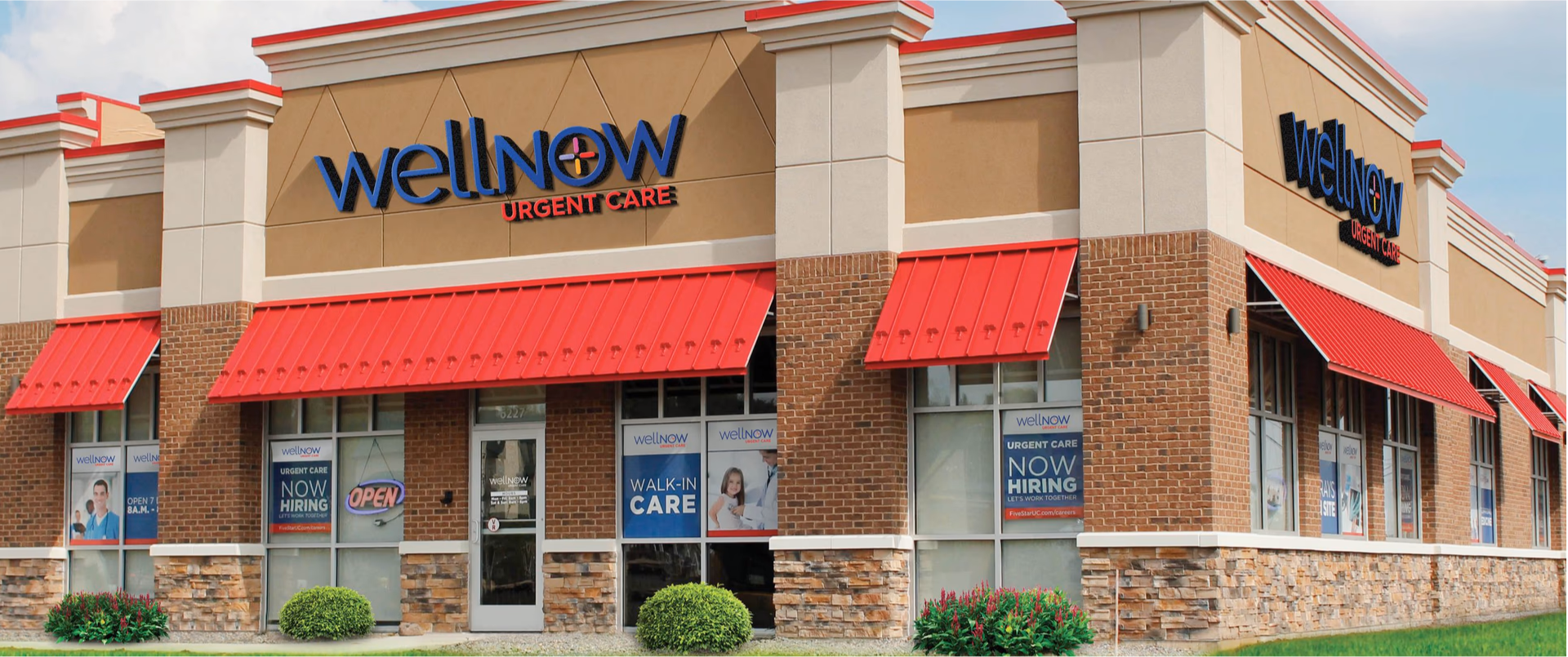 Exterior view of a WellNow Urgent Care center, with red awnings above the windows.  