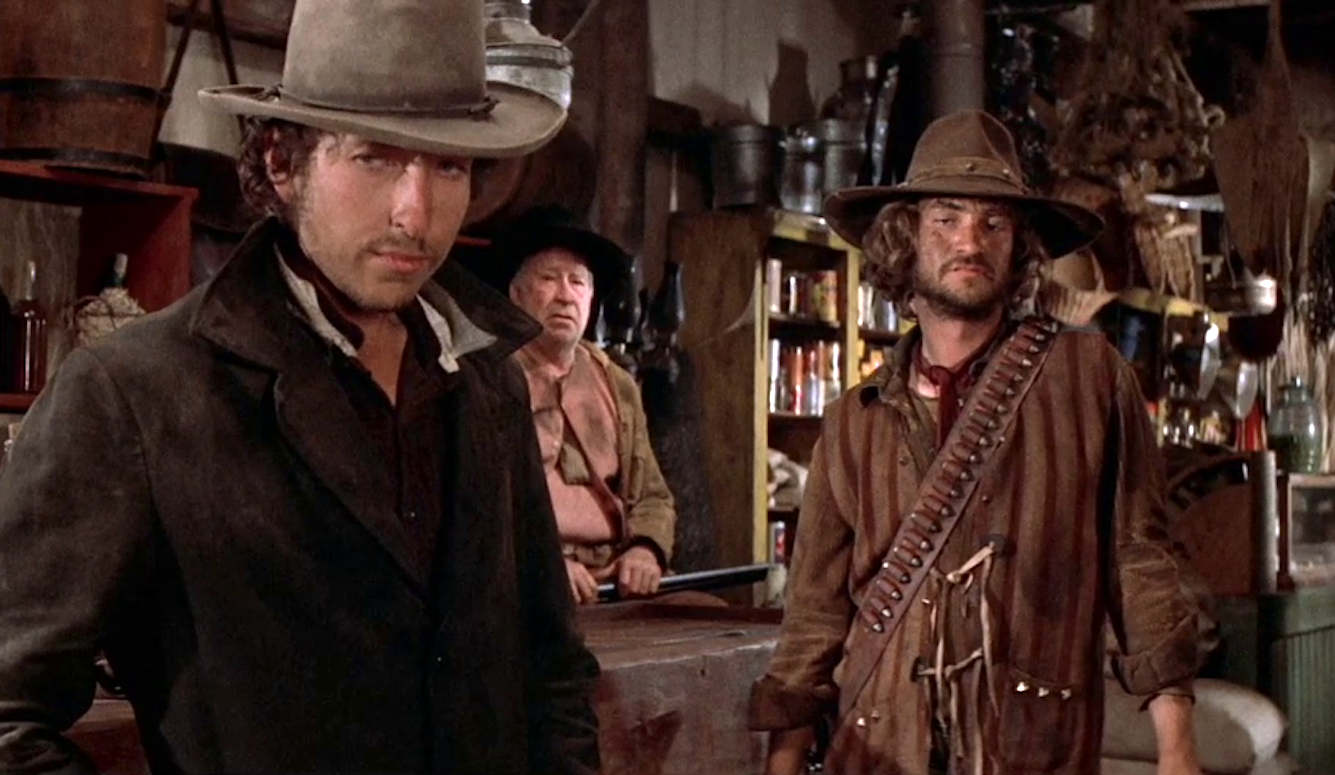 The photo shows a young Dylan in stetson and cowboy outfit in a saloon. 