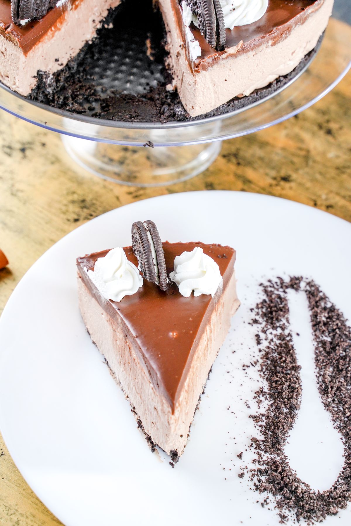 view looking down at slice of cheesecake on white plate with cookie crumbs