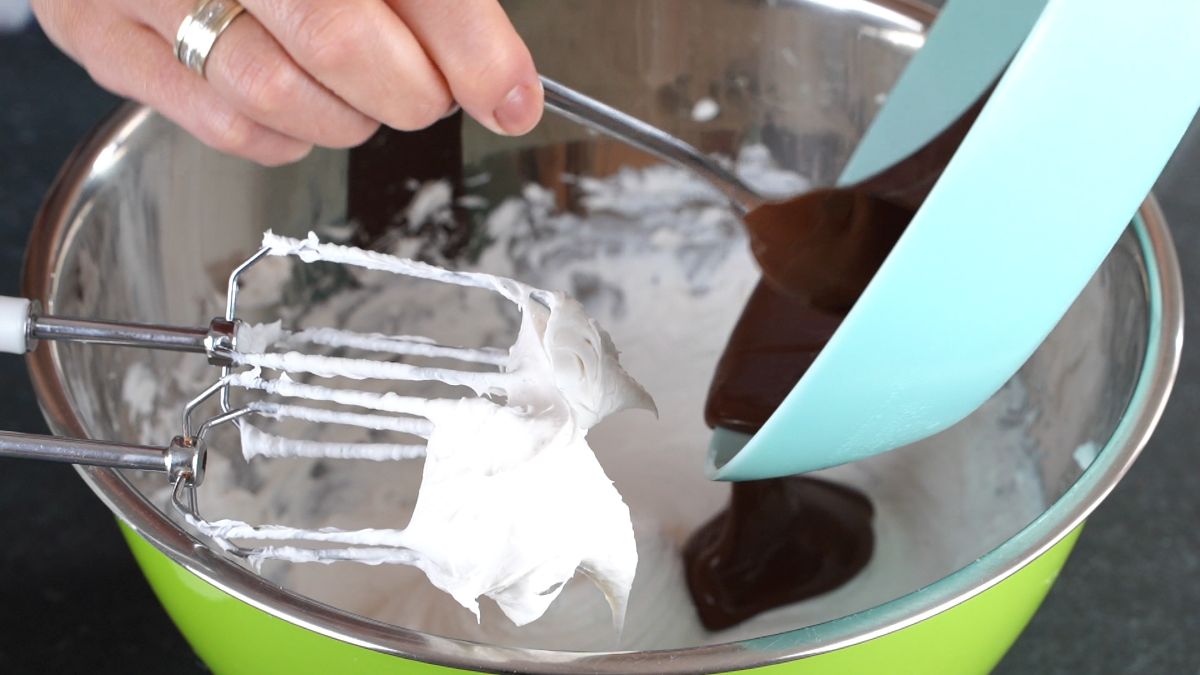 hand spooning chocolate into cream cheese