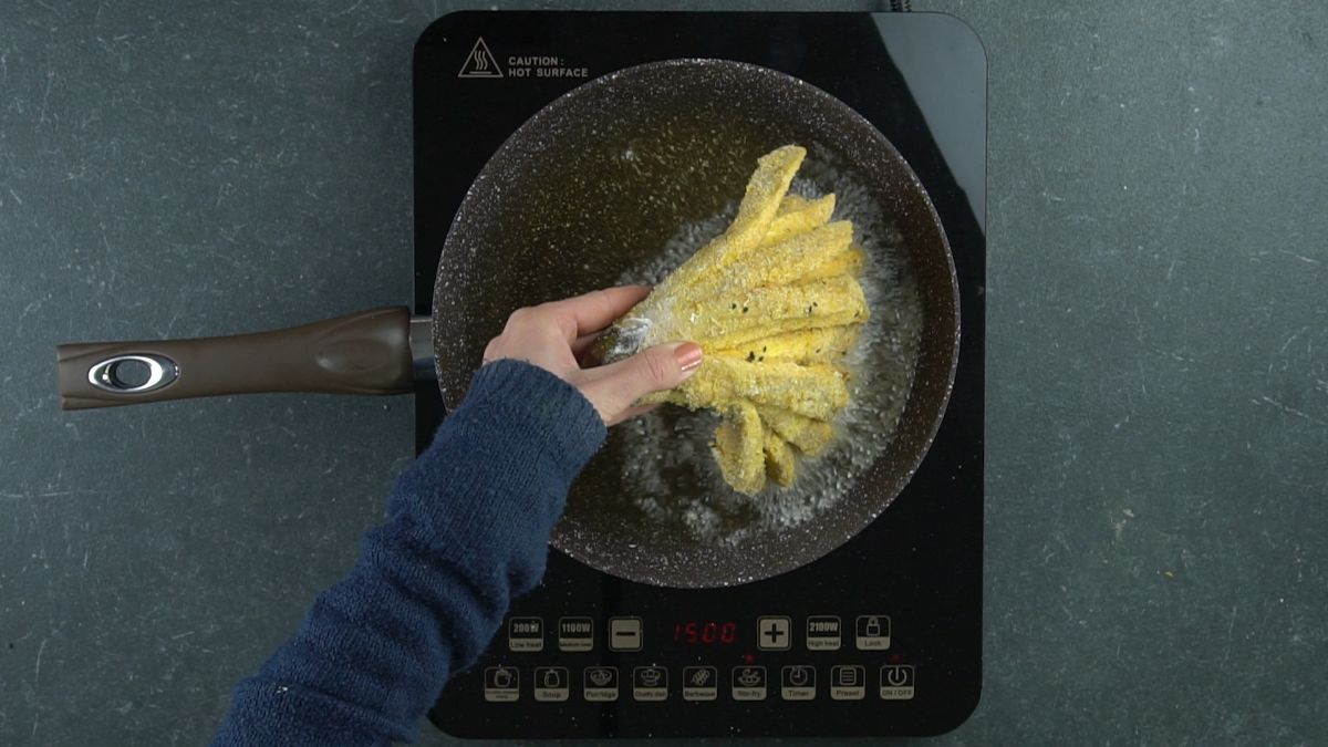 eggplant being fried in skillet on hot plate