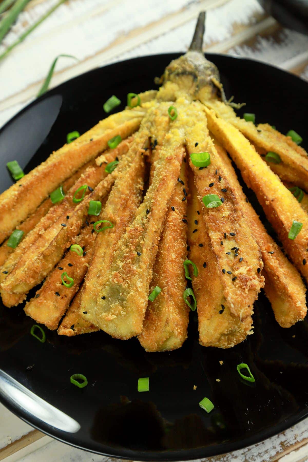 whole fried eggplant on black plate