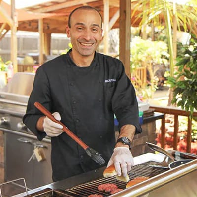 BBQGuys employee smiling and showing off his BBQ