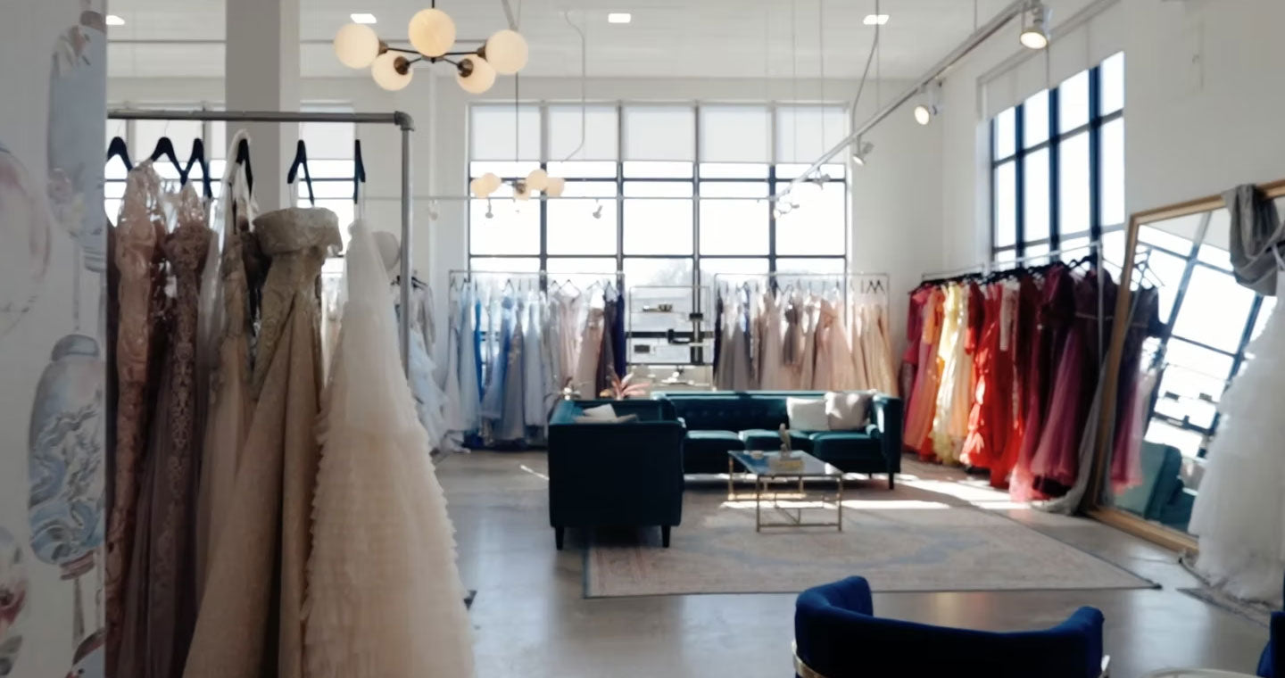 Gowns of all colors hang on racks in a sun drenched room