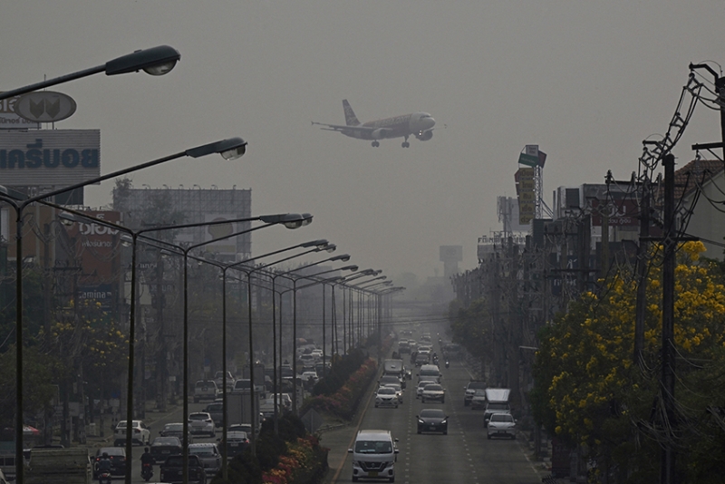 An aeroplane flies over a road in Chiang Mai, Thailand. 