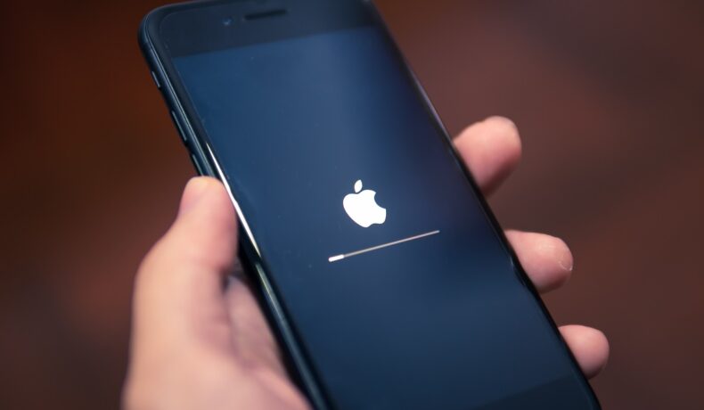 Telefon iPhone, ținut în mână de un utilizator, în timp ce se actualizează. Apple avertizează toți utilizatorii iPhone să instaleze actualizarea 15.4.1