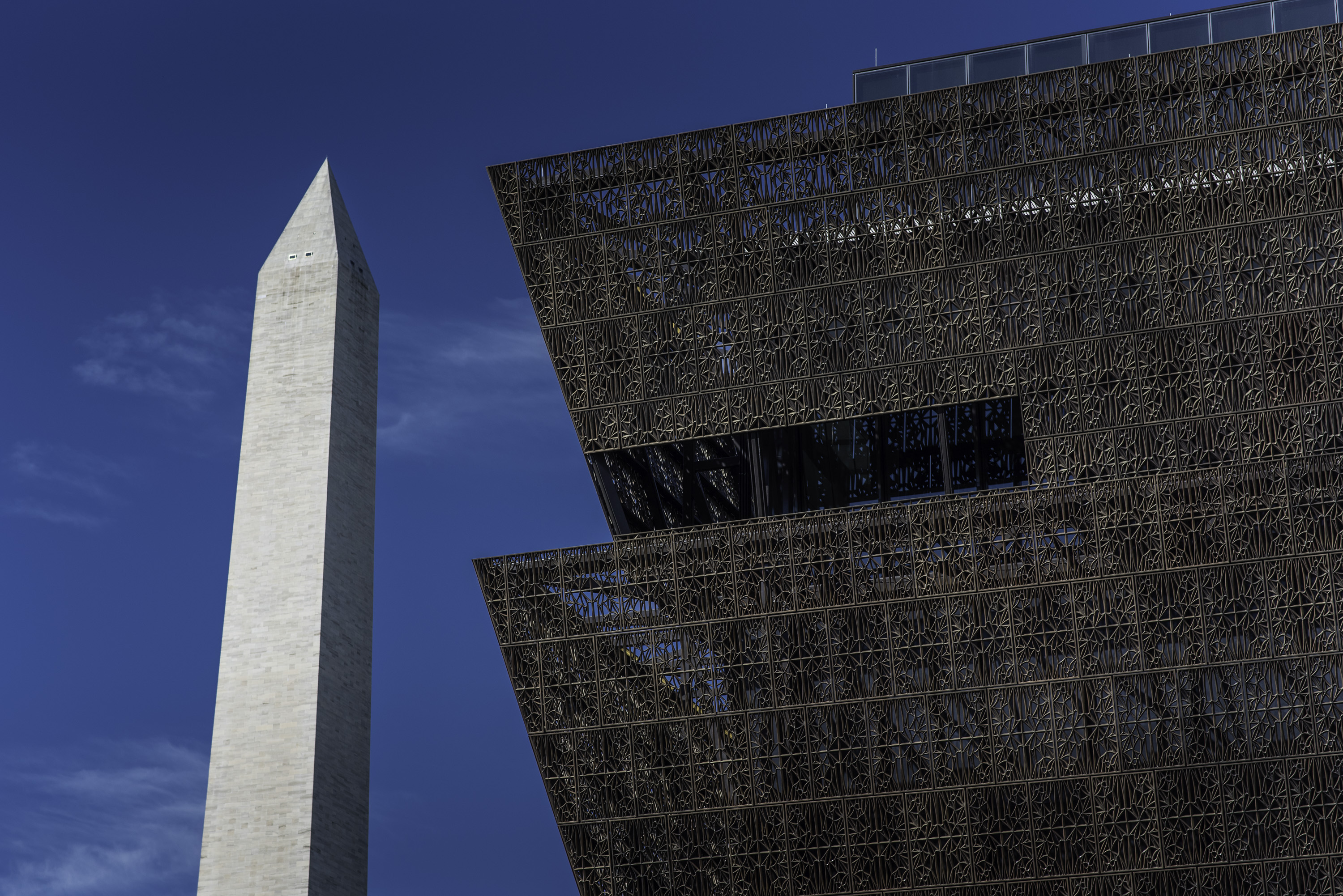 Shot of Washington Monument alongside the copper edges of a tiered copper building. 