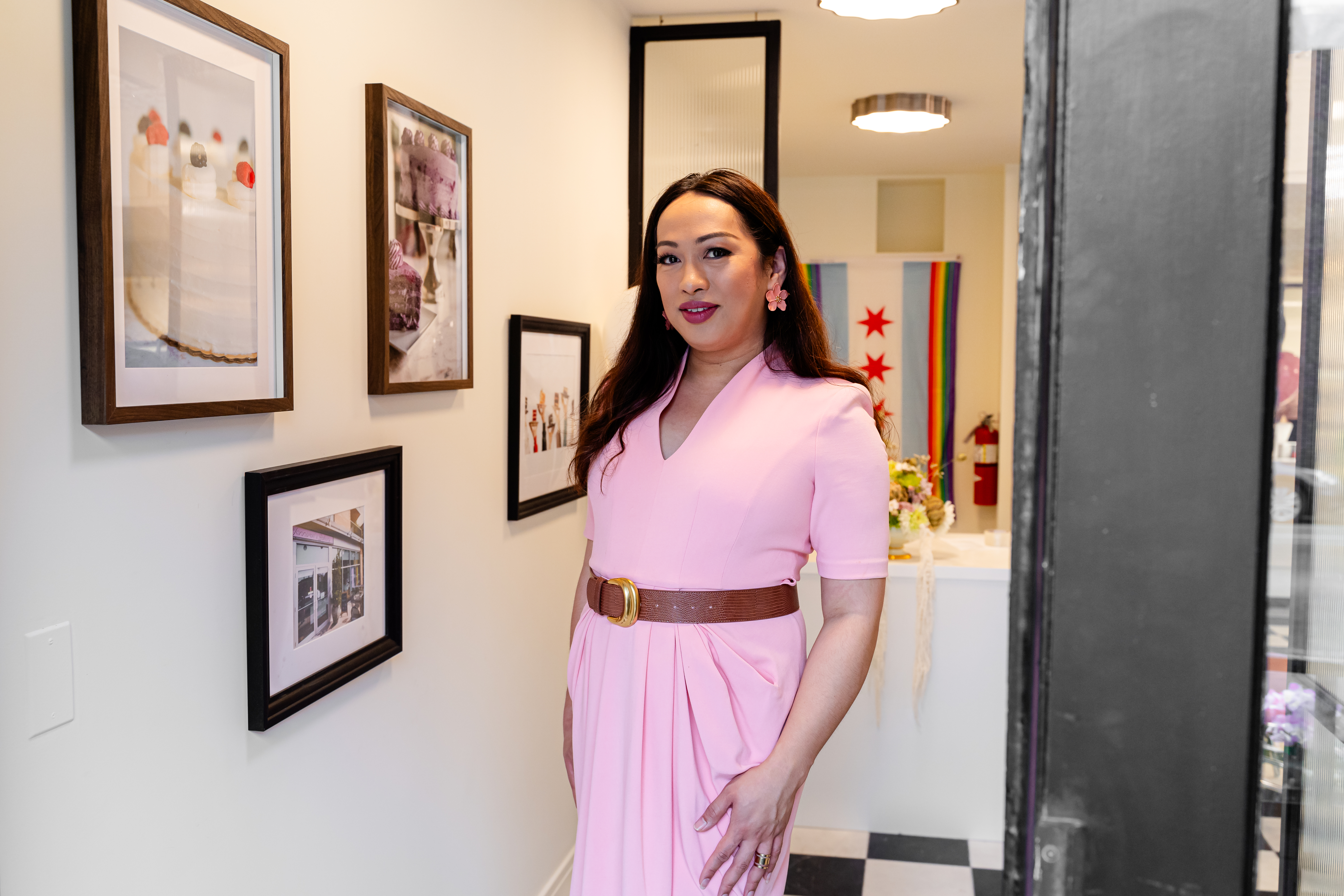 Jenni Vee poses inside her bakery in front of a Chicago Pride flag.