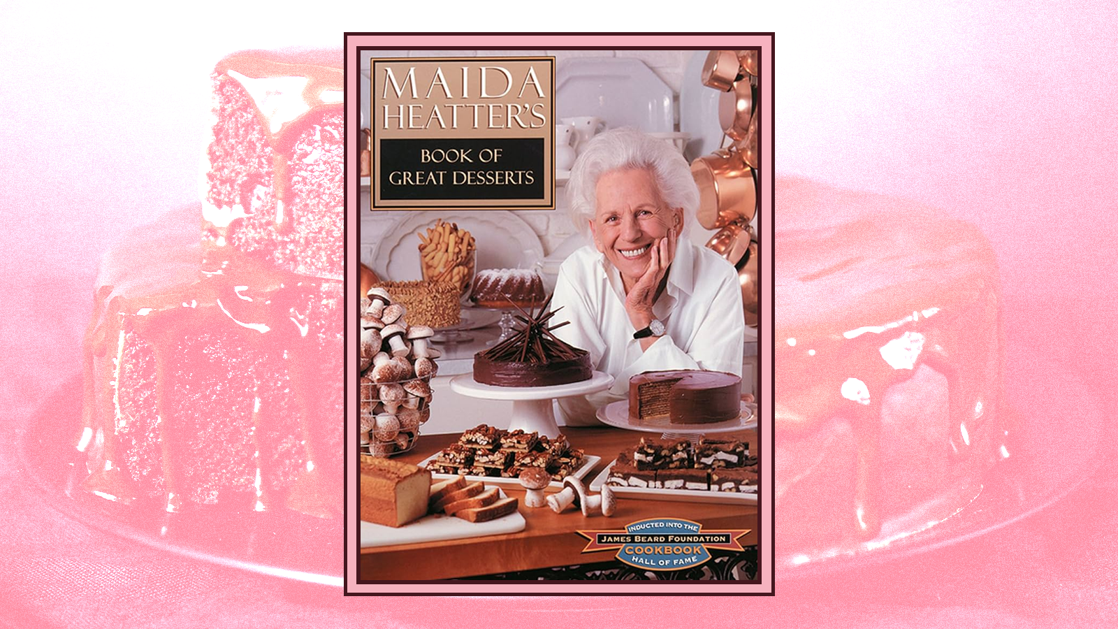 The cover of “Maida Heatter’s Book of Great Desserts” against a pink stylized photograph of a cake.