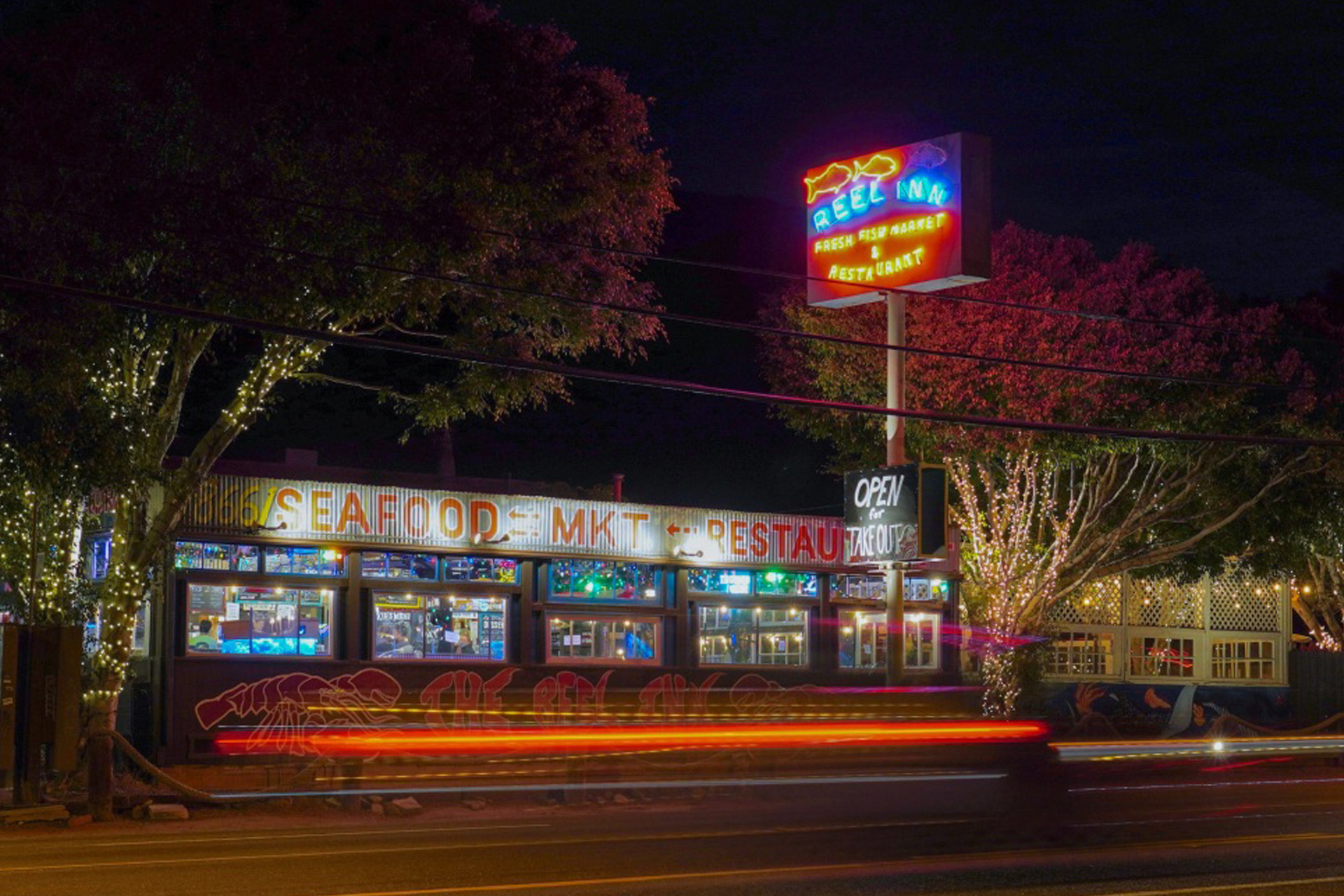 The Reel Inn restaurant in Malibu in the evening with a sign illuminated by a neon pylon sign.