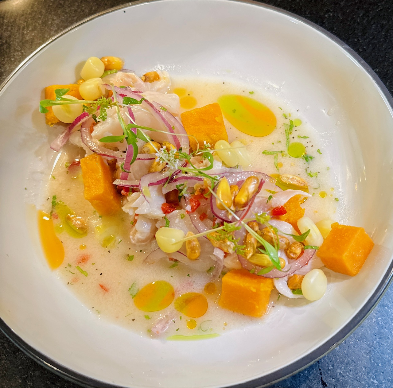 A plate of ceviche garnished with red onion at Alora.