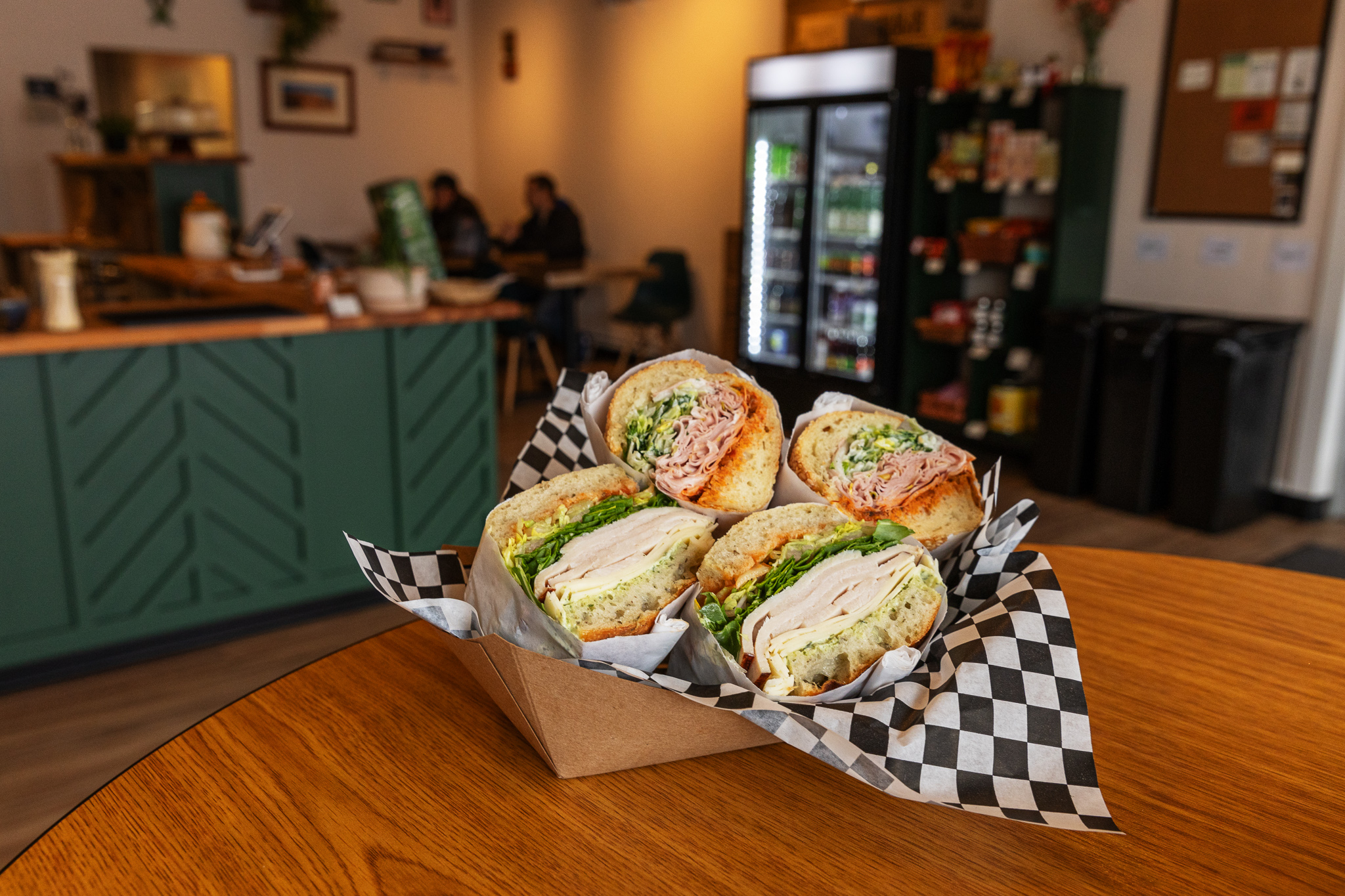 Two sandwiches in a paper boat on a table at Tall Trees Cafe in Ferndale, Michigan.