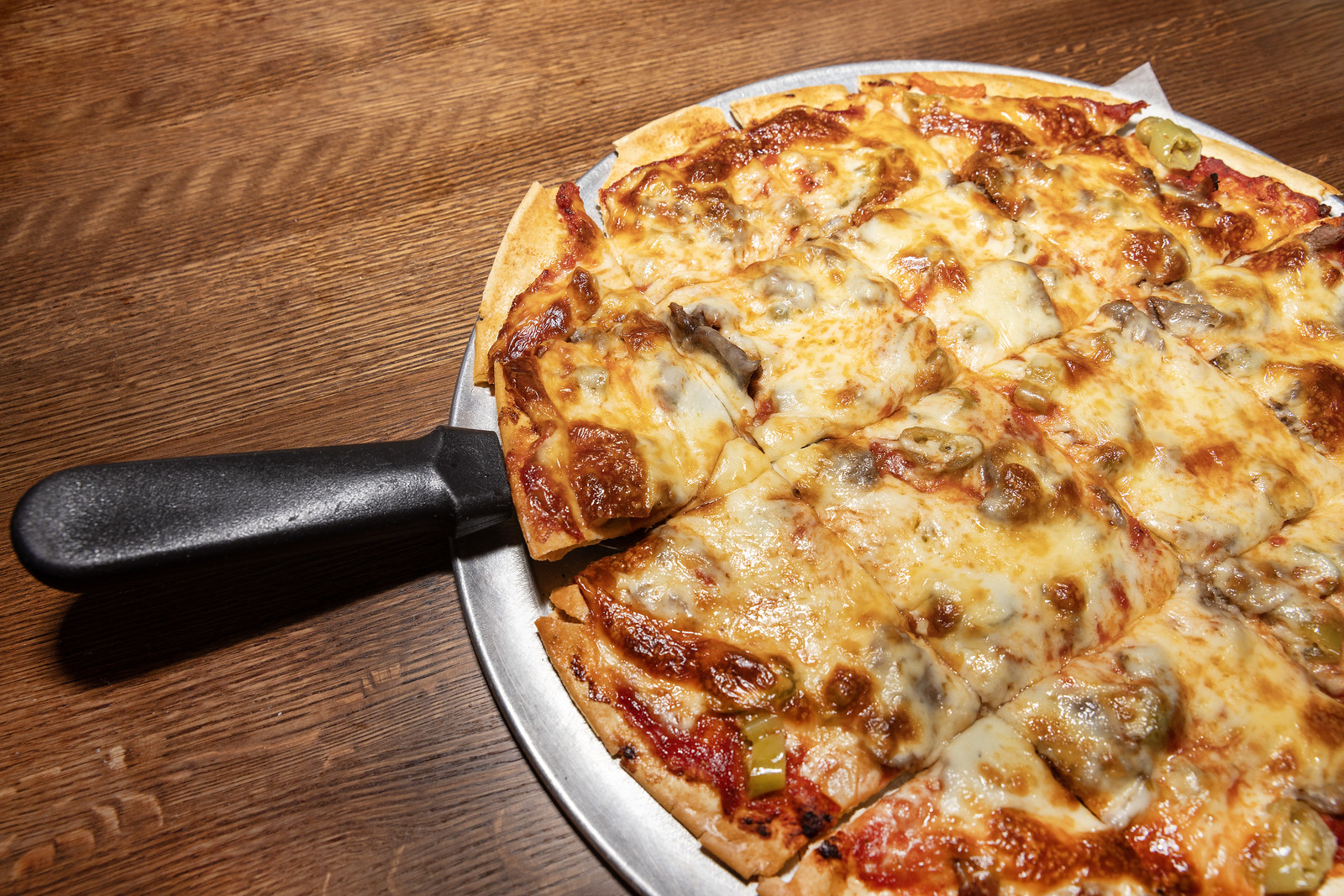 A tavern style pizza with a spatula.