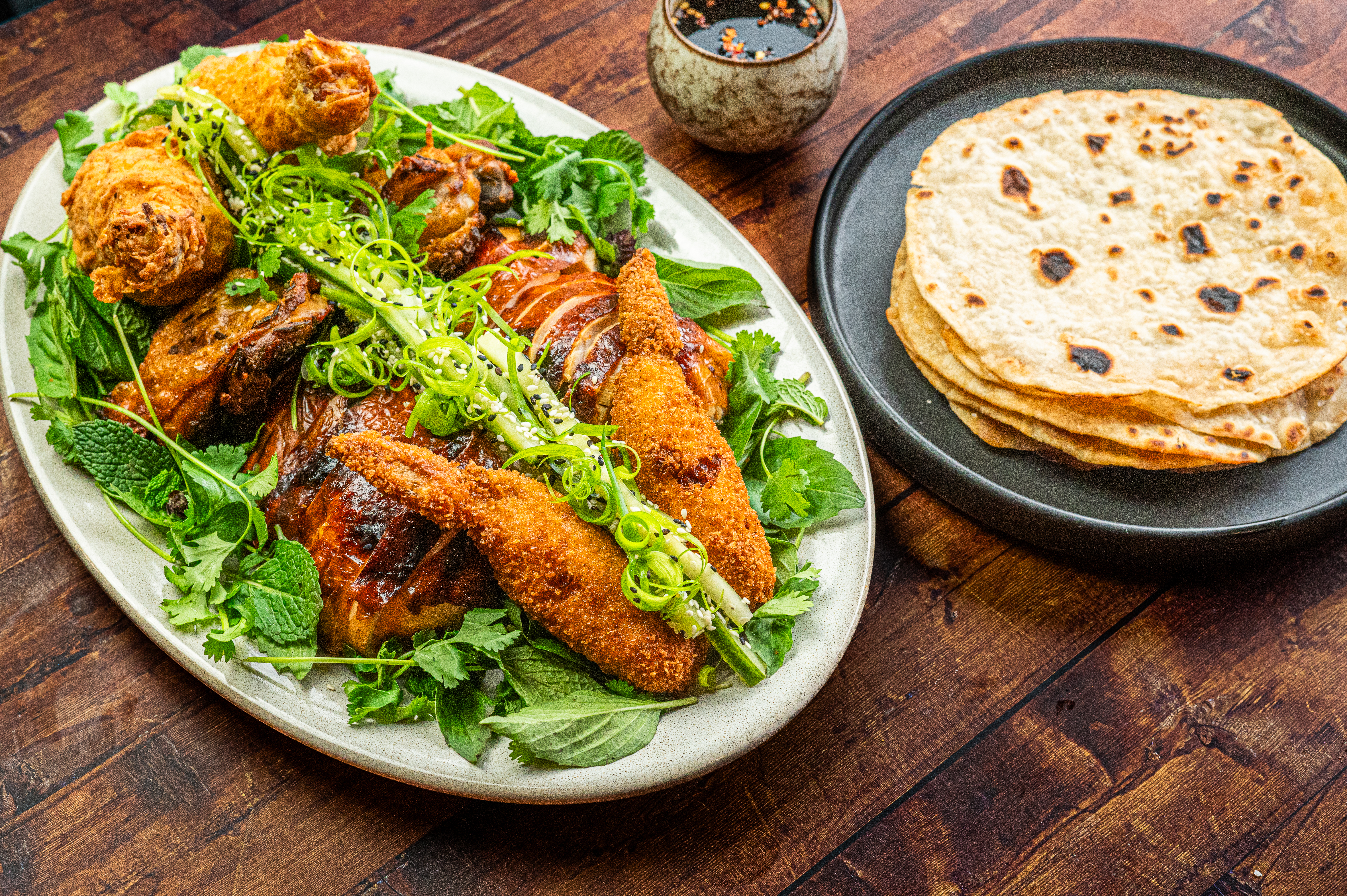 “All of the Chicken,” a whole bird prepared four ways: crispy fried legs, duck fat- confit thighs, Beijing-style cured, and roasted breast, and a stuffed chicken wing – served with a Mandarin pancake from Echelon Kitchen &amp; Bar in Ann Arbor, Michigan.