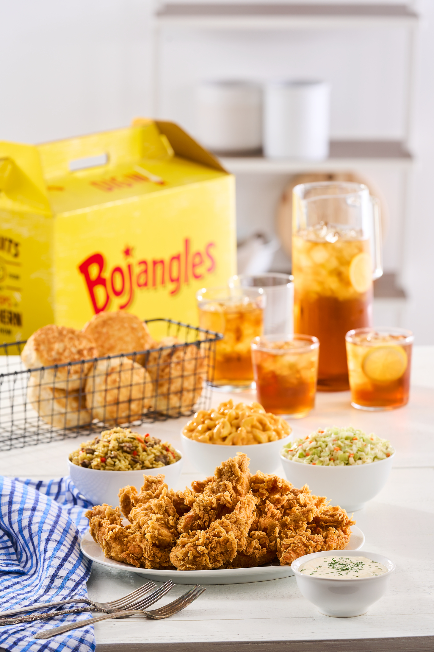 Plates of Bojangles fried chicken and biscuits and cups of lemonade sit on a table.