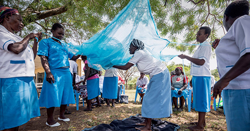 Women showing the use of a insecticide-treated net