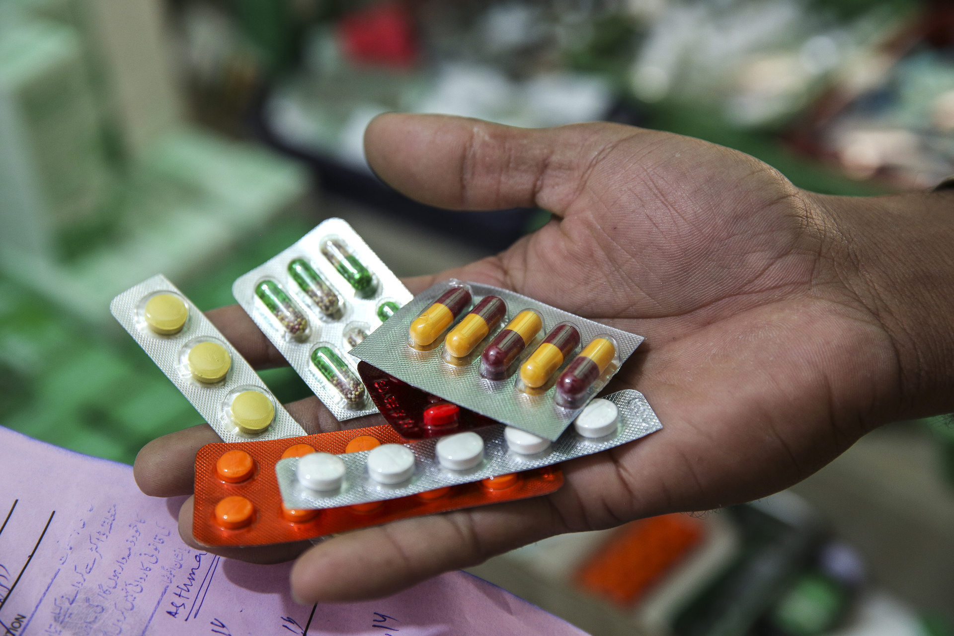 Several packages of different pills in a person's hand