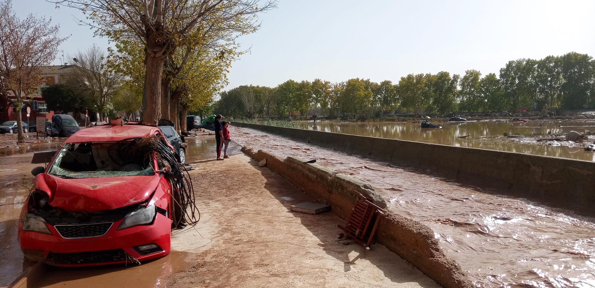 View of street after violent floods, with mud, water and cars.