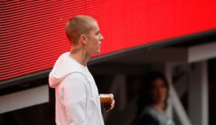 Justin Bieber îmbrăcat cu un hanorac alb, ținând o băutură în mână