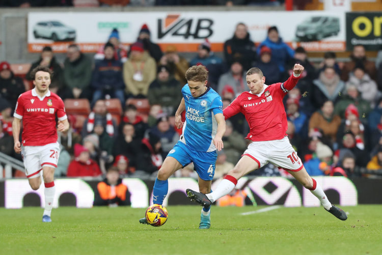 Archie Collins of Peterborough United competes with Paul Mullin of Wrexham AFC during the Sky Bet League One match between Wrexham AFC and Peterbor...