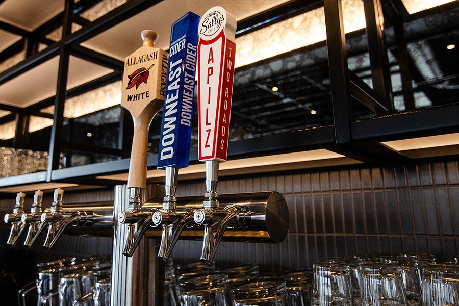 Closeup on beer taps, including Allagash White, Downeast Cider, and Two Roads Brewing.