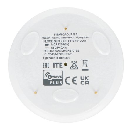 The white and round Fibaro flood sensor lies on a white background.