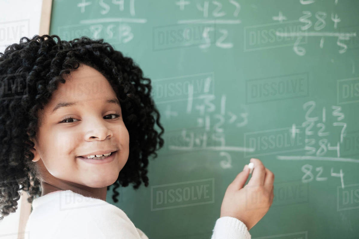 African American student writing on chalkboard in classroom - Stock ...