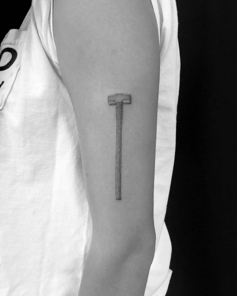 Single needle sledgehammer tattoo on the upper arm