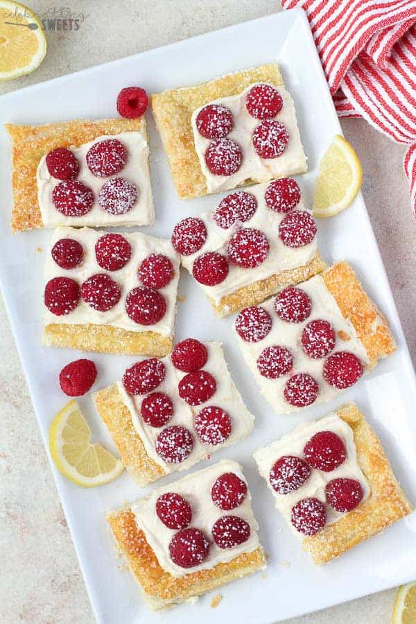 Slices of Lemon Tart topped with Raspberries on a White Platter.