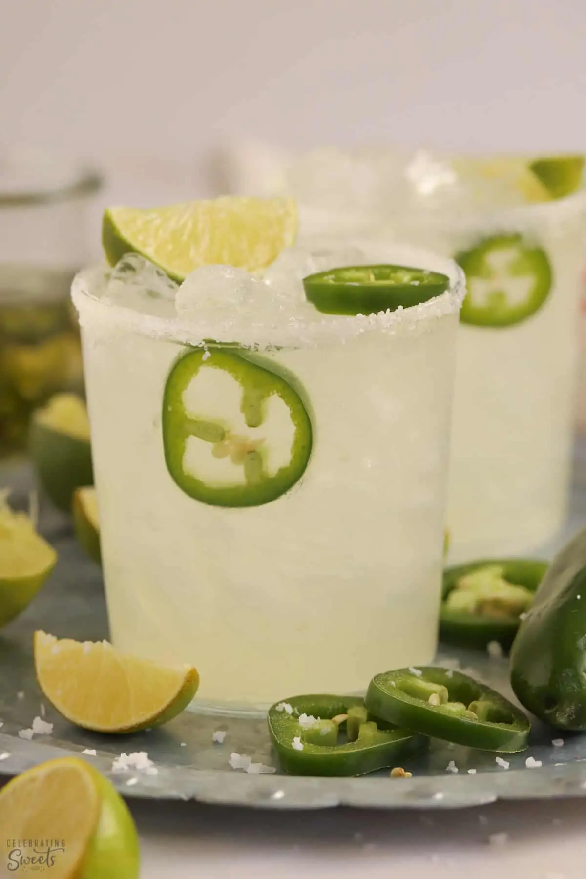 Spicy Margarita in a glass on a tray garnished with lime and jalapeno slices.