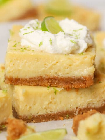 Stack of two key lime pie bars topped with whipped cream.