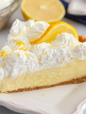 Slice of lemon cream pie on a white plate with a silver fork.