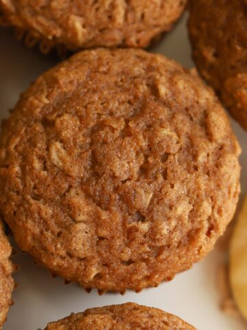 Overhead photo of an apple oatmeal muffin next to a spoon of applesauce.