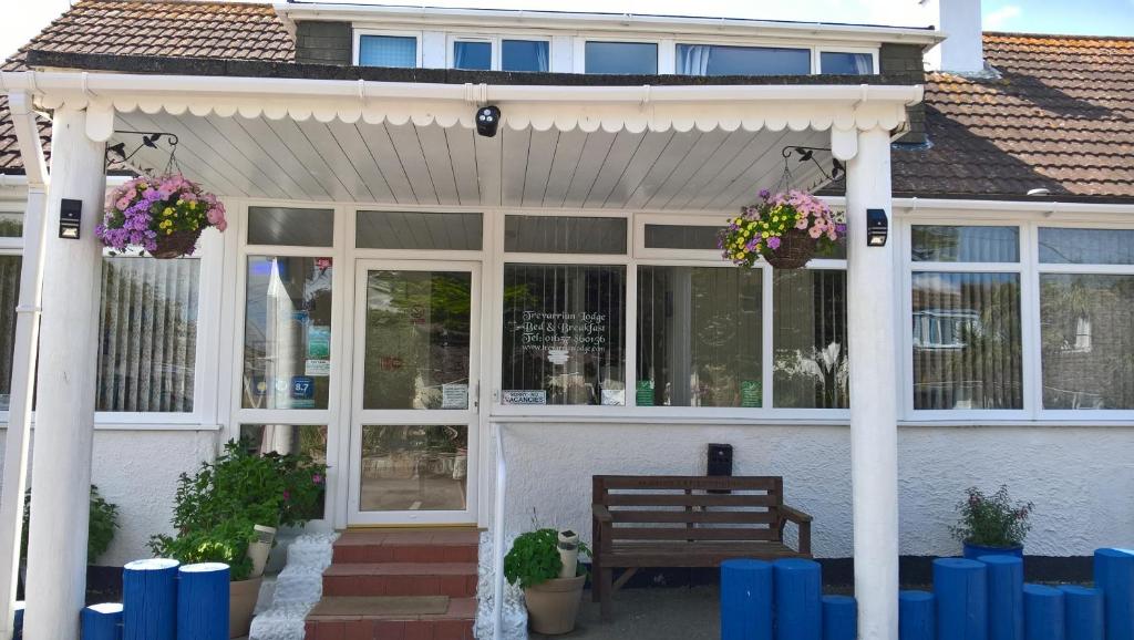 a white house with a pergola and a bench at Trevarrian Lodge in Newquay